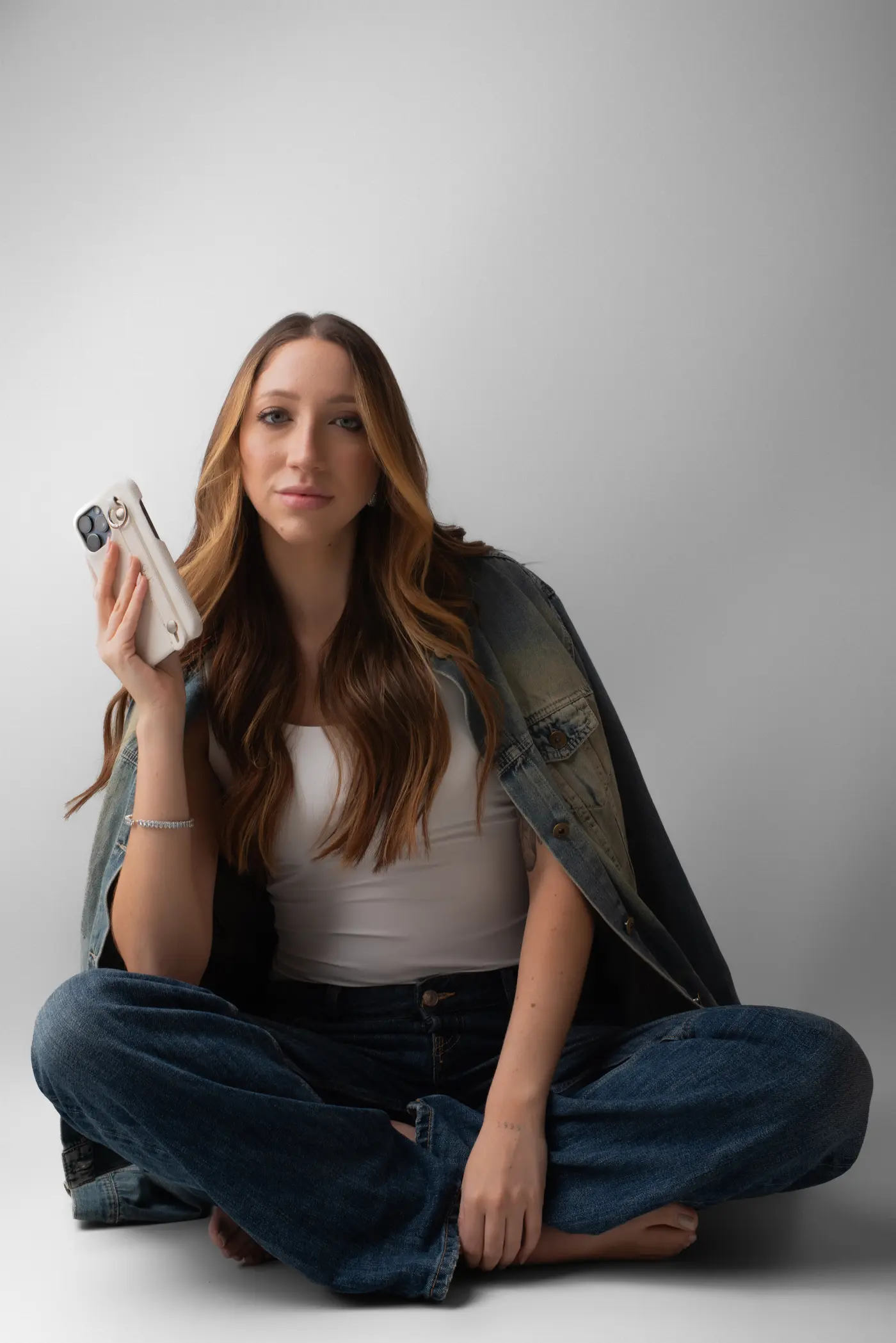 Giulia Toledo sentada com o celular na mão, olhando para a câmera